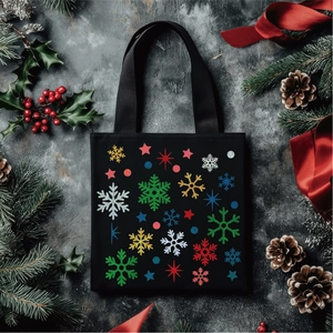 Close-up of black canvas tote bag with festive gold glitter snowflake and star prints