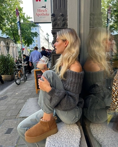 Détail d'un pull en maille gris à épaules dénudées avec jean bleu clair et bottines à plateforme