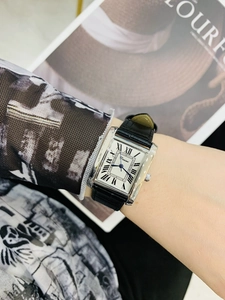Close-up of a rectangular silver ladies watch with black leather strap on a wrist