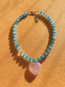 Macro detail of cat eye stone beads and a pink heart crystal pendant on the necklace
