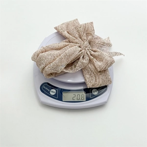 Detail shot showing the lightweight 20.8g weight of the beige floral ribbon bow hair clip