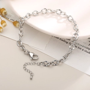 Detail of silver textured oval link anklet with lobster clasp on a white plate