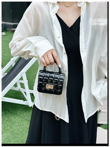 Detailed view of black quilted jelly bag with gold chain strap and turn-lock closure
