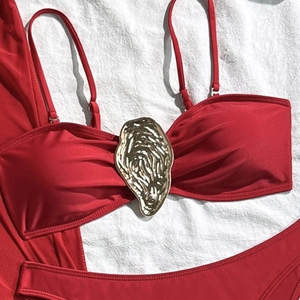 Detail of red bikini top with adjustable straps and a golden oyster shell metal clasp