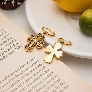 Detail of gold cross earrings with brown enamel and crystals on vintage book