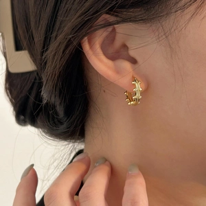 Close-up of elegant gold beaded hoop earrings worn by a model for a chic style