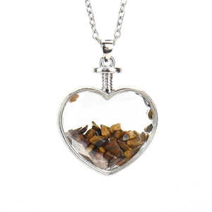 Macro shot of heart-shaped glass pendant filled with polished tiger eye stone chips