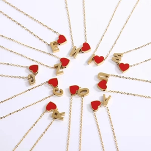 Macro detail of gold necklaces with red heart pendants and assorted alphabet charms