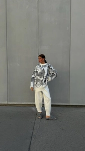 Detail of white knit sweater set with dark gray print and matching pants on a model