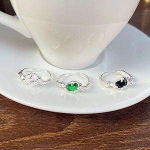 Detailed view of silver rings featuring white, emerald green and black gemstones