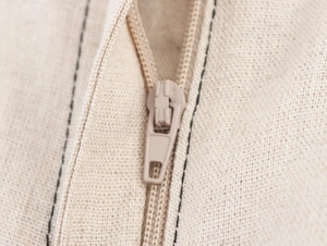 Gros plan détaillé d'une fermeture éclair beige sur un ensemble haut et pantalon