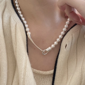 Detailed view of a minimalist pearl necklace with a unique silver clasp on a model