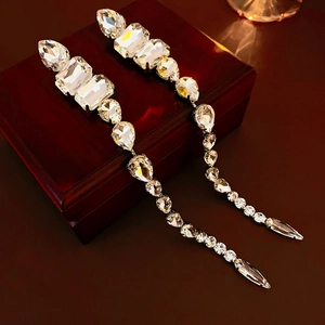 Macro shot of silver tassel earrings with sparkling teardrop rhinestones on a red jewelry box