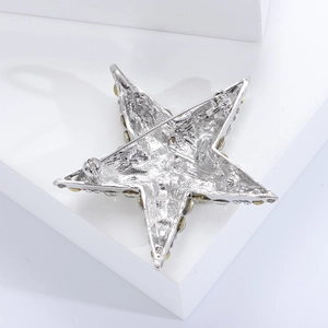 Detailed back view of a silver star brooch with safety pin fastener and yellow gemstones