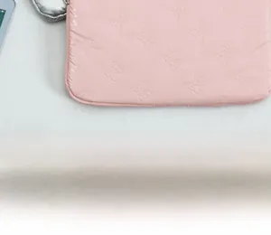 Detailed view of pink quilted laptop sleeve with embossed 3D bow patterns and soft texture