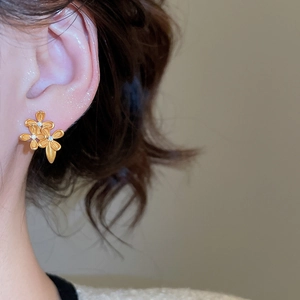 Detail of 24K gold plated flower stud earrings with shimmering zircon inlays on ear