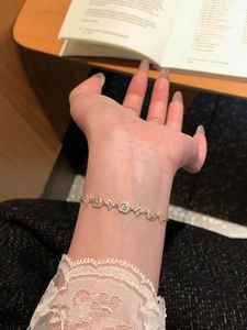 Close-up of 18K gold plated bracelet with zircon floral charms on a female wrist