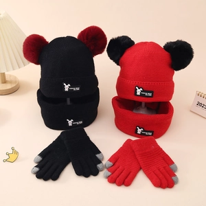 Detail of children's knit set showing double-pompom hat with rabbit patch and touch gloves