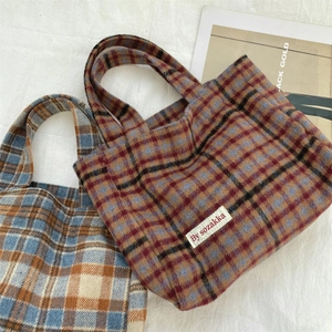 Macro view showing detailed wool fabric texture of red and blue plaid tote handbags
