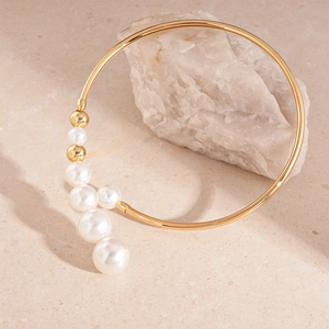 Macro view of gold open choker featuring white pearls on textured stone surface