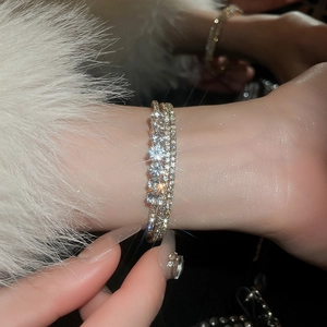 Close-up of a multi-layer gold bracelet with shimmering zircon stones on a model's wrist