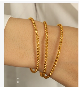 Detailed close-up of a stack of three gold twisted rope bangles on a woman's wrist