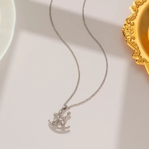Detail of silver balloon dog necklace on curved rocking horse pendant with delicate chain