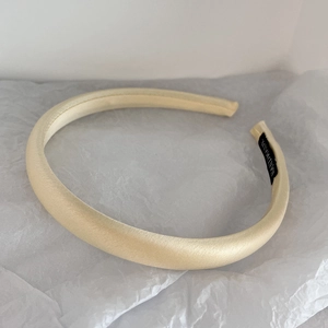 Close-up of a handmade cream satin headband on white paper texture background