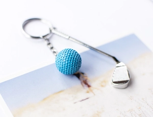 Detailweergave van creatieve golfbal- en club-sleutelhanger met blauwe getextureerde bal