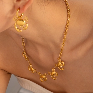 Close-up of gold-plated stainless steel necklace and earrings with crab motifs on a model