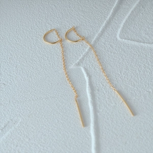 Detail view of gold geometric chain earrings featuring D-shaped hooks and long tassels