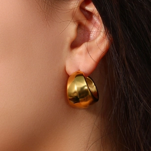 Détail de créoles épaisses plaquées or 18 carats portées sur une oreille de mannequin