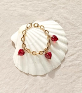 Detail of vintage gold-plated chain bracelet with red glass heart pendants and OT toggle clasp