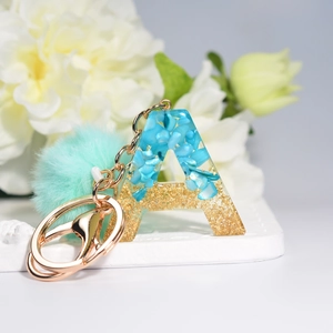 Blue resin letter A keychain with gold foil flakes and mint green pompom accessory