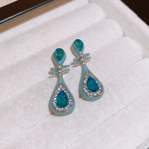 Detailed macro view of teardrop sapphire earrings with blue enamel and crystal inlay