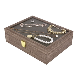 Wooden jewelry box with glass lid, vintage lock, and soft velvet interior for storing rings and necklaces.