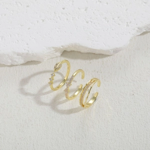 Detailed macro view of three golden bow rings with zircon inlay on a white stone background
