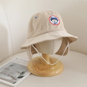 Détail d'un chapeau cloche beige en velours pour enfant avec broderie d'ours et cordon