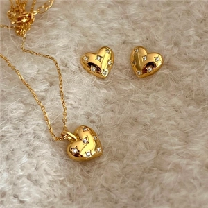 Macro detail of golden heart-shaped necklace and earrings set with star motifs