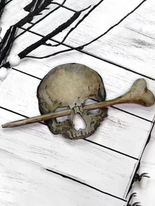 Close-up of gothic skeleton skull and bone hair pin on a rustic wood background