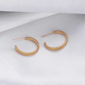 Detail of 18K gold plated C-shape hoop earrings with twisted texture and zircon inlay