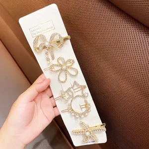Detail of 5-piece gold hair clip set with pearls and rhinestones on a white card