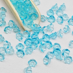 Macro shot of light blue lily of the valley glass beads spilling from a wooden spoon