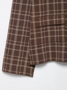 Detailaufnahme von braunem und beigem Karo-Strickstoff mit Taschennaht und Saumstruktur