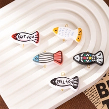 Detail view of five colorful salt fish pendants on a textured white display tray
