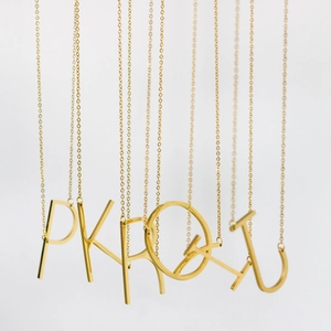 Close-up of gold plated stainless steel initial letter necklaces showing P K R O Q I U