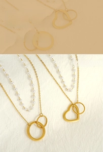 Detail of double-layer necklace with gold heart pendant and artificial pearls decoration