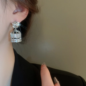 Elegant silver cage earrings with faux pearls and sparkling zircons worn by a model