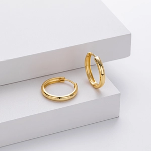 Close-up of polished 925 sterling silver hoop earrings with gold finish and inner stamp