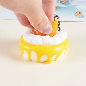 Realistic yellow PU foam squishy cake with white cream and fruit toppings being squeezed